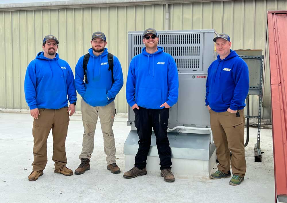 Three Air-Man Heating and Air technicians standing together outside