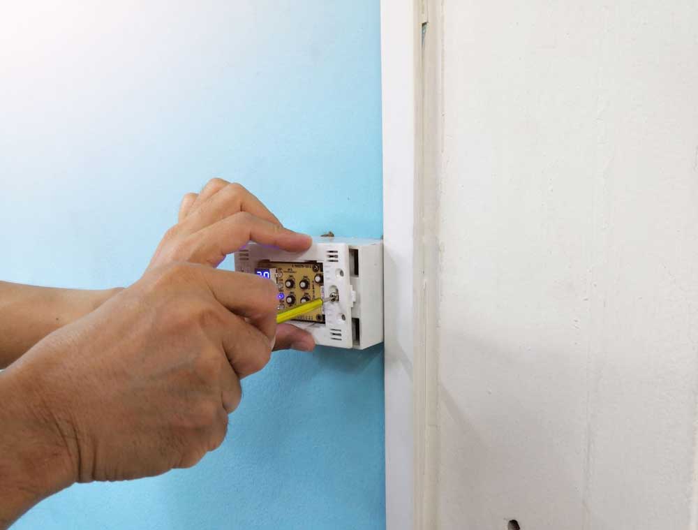 Hand adjusting a smart thermostat mounted on a wall
