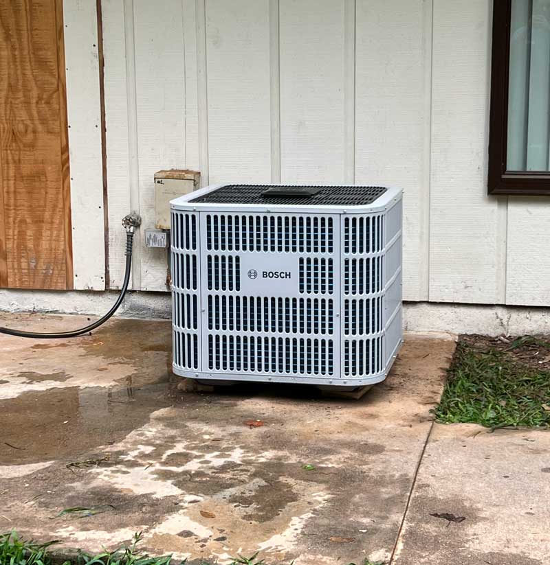 Outdoor air conditioning condenser unit installed beside a house