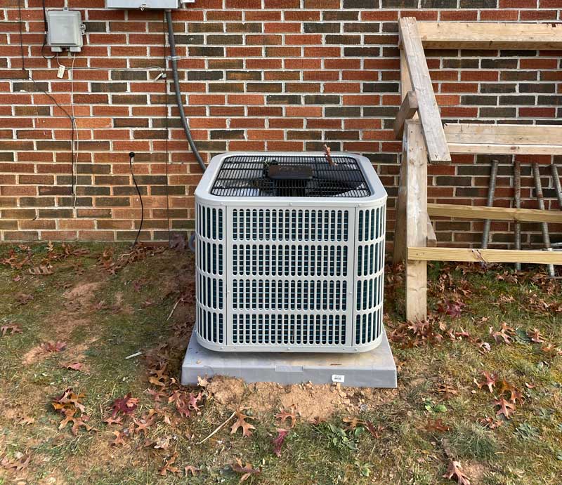 Outdoor air conditioner condenser unit beside a brick home