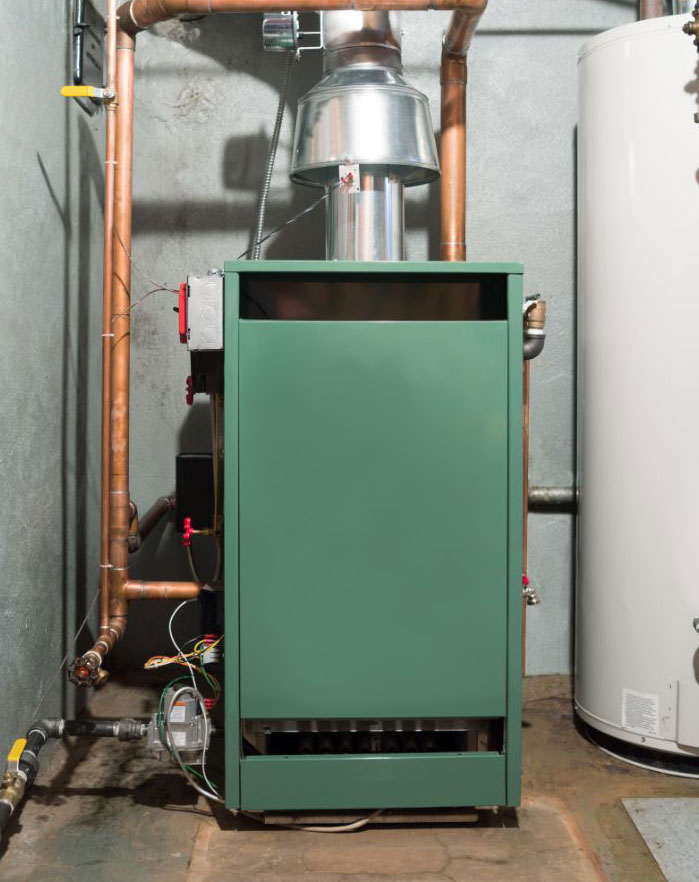 Green boiler-style furnace and water heater in a basement utility area