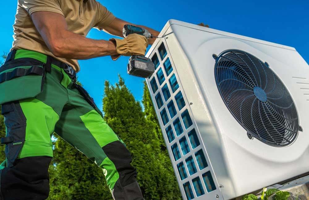 Technician removing the top panel from an outdoor heat pump unit