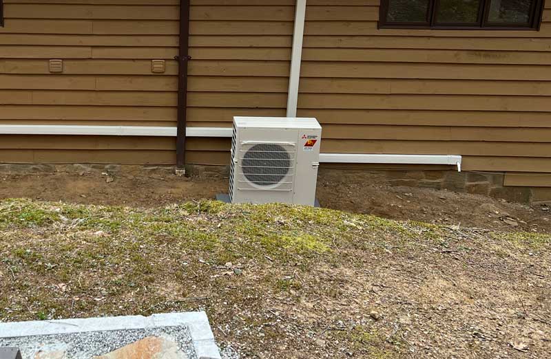Outdoor heat pump unit installed beside a home's exterior wall