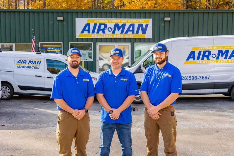 Three Air-Man Heating and Air technicians standing in front of a service van